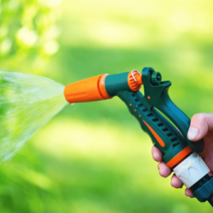A gardener watering the garden using garden hose sprayer gun nozzle